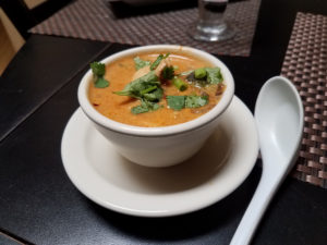 A bowl of soup on top of a white plate.