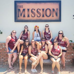 A group of women standing in front of the mission sign.