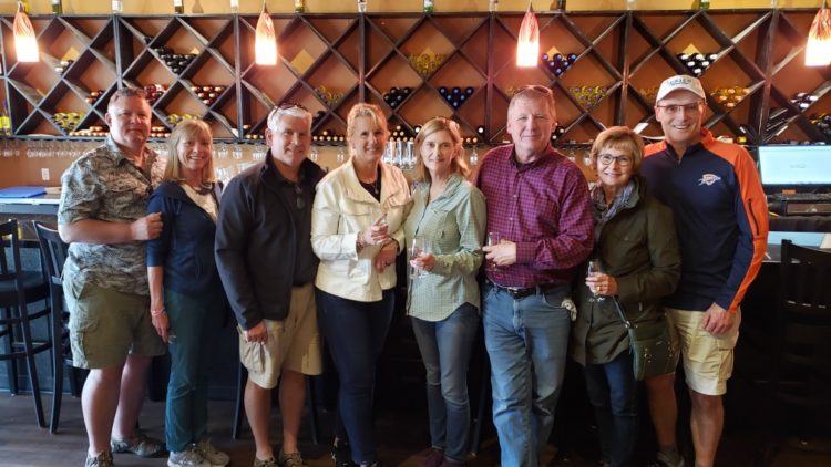 A group of people standing in front of some wine bottles.